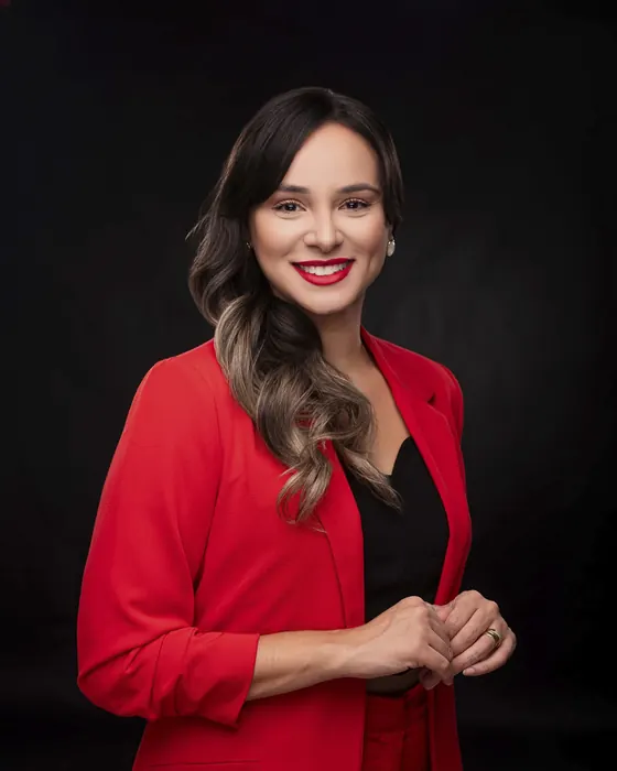 Mulher de blazer vermelho sobre preto em retrato corporativo de estúdio