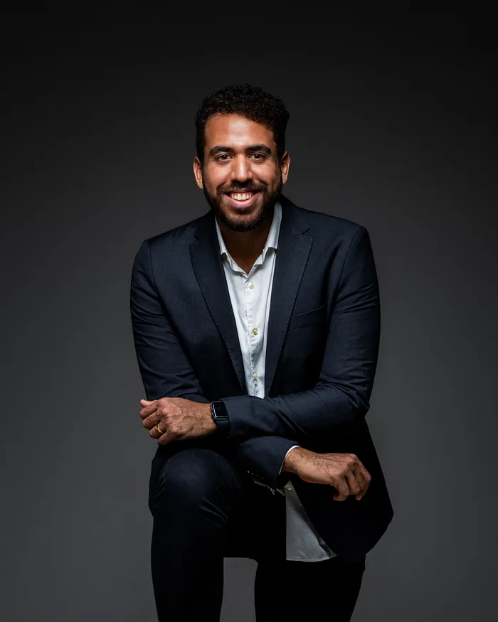 Homem de blazer escuro e camisa clara em retrato corporativo de estúdio